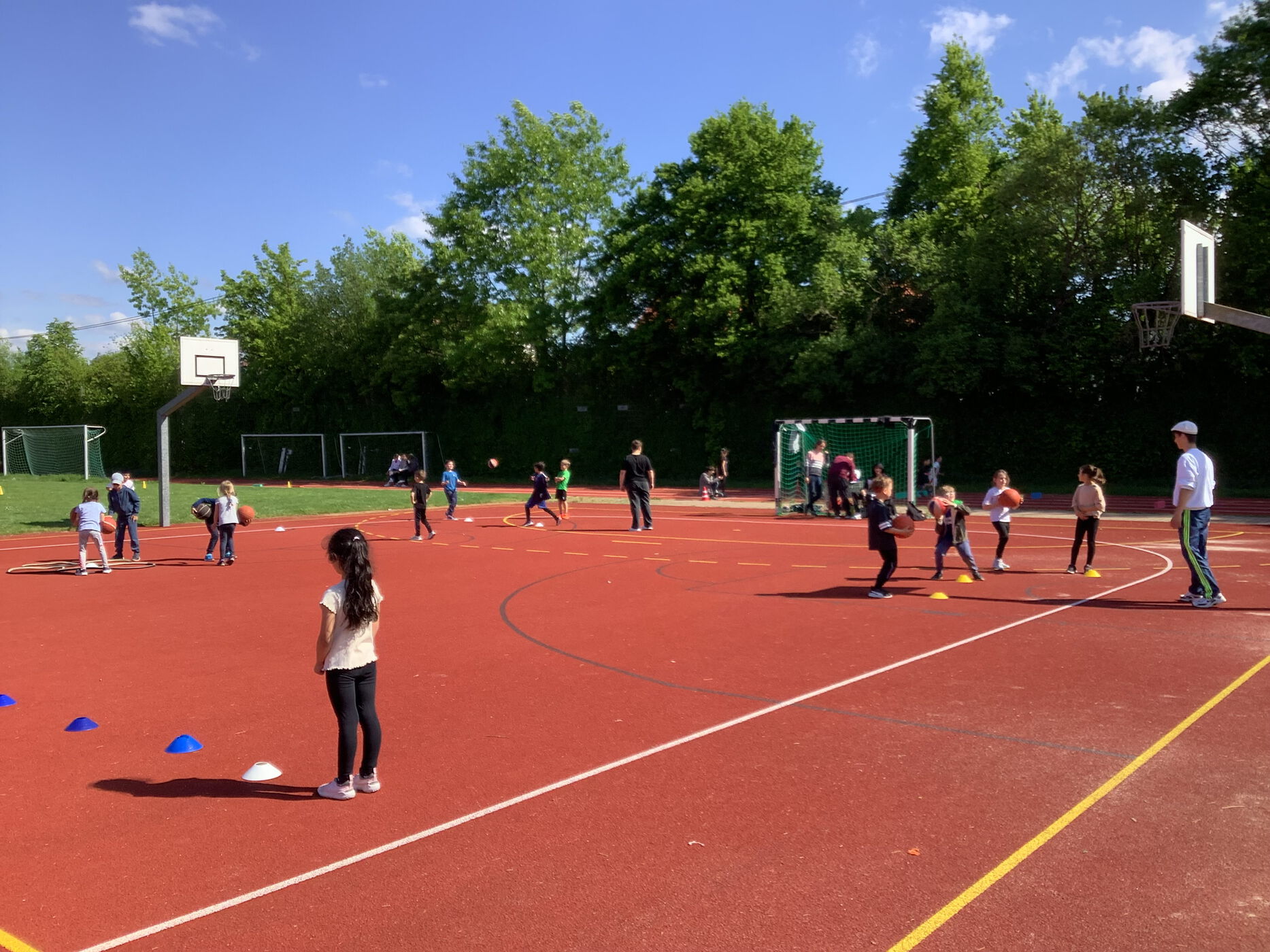Kinder spielen verschiedene Ballsportarten auf dem Sportplatz